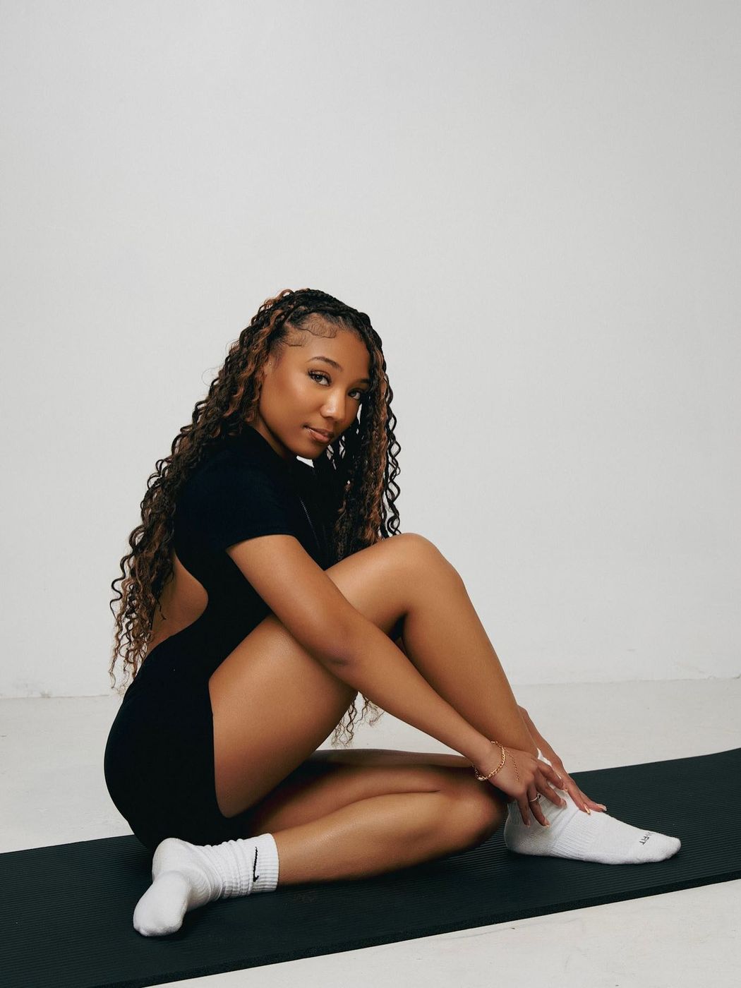 Woman in a black Bellz bodysuit sitting on a mat